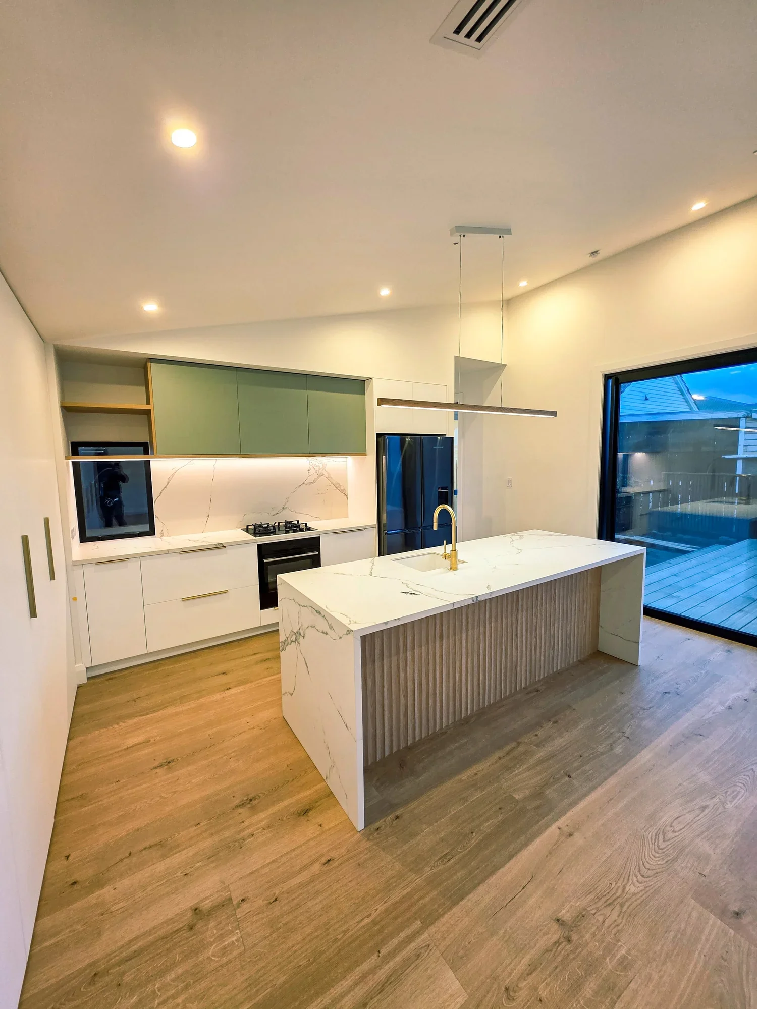 Bespoke kitchen with sage cabinetry, stone island and timber floors