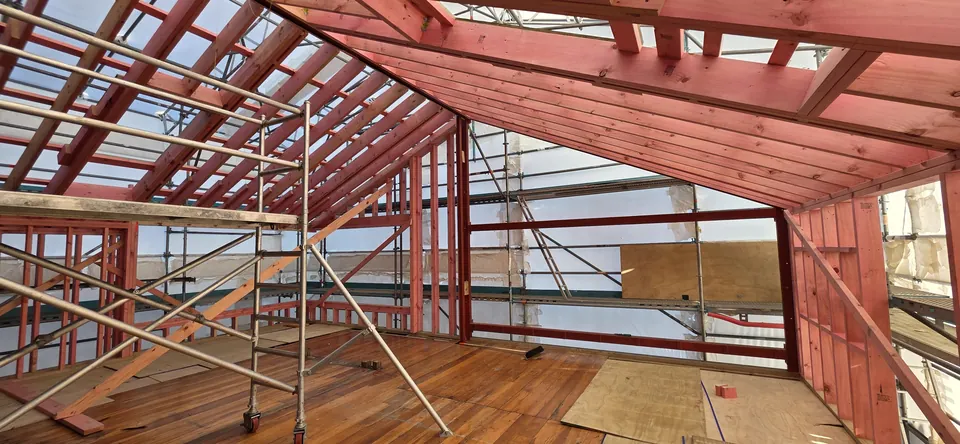 Timber roof framing and structural steel beneath the scaffold canopy
