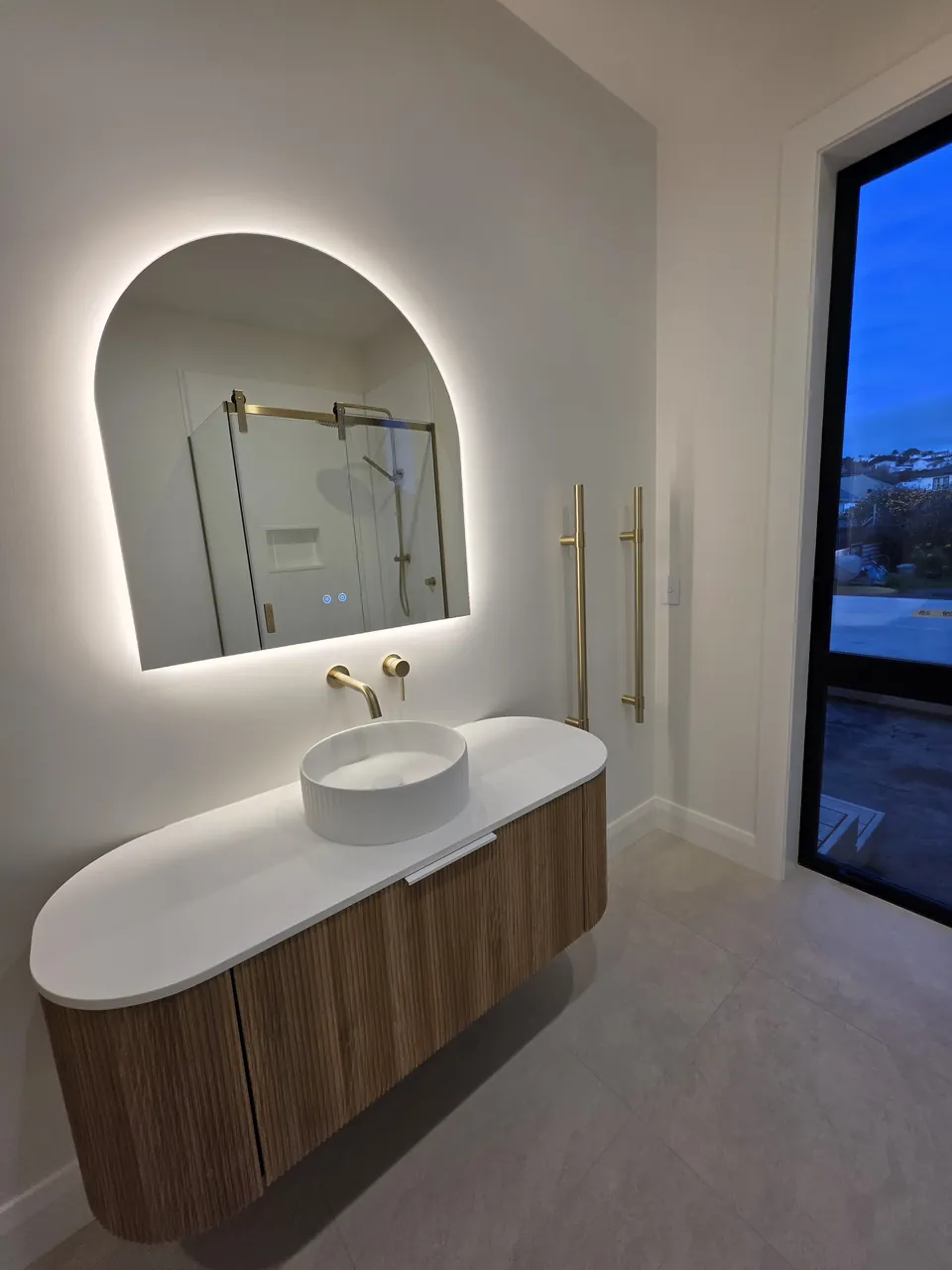 Bathroom vanity and illuminated arched mirror